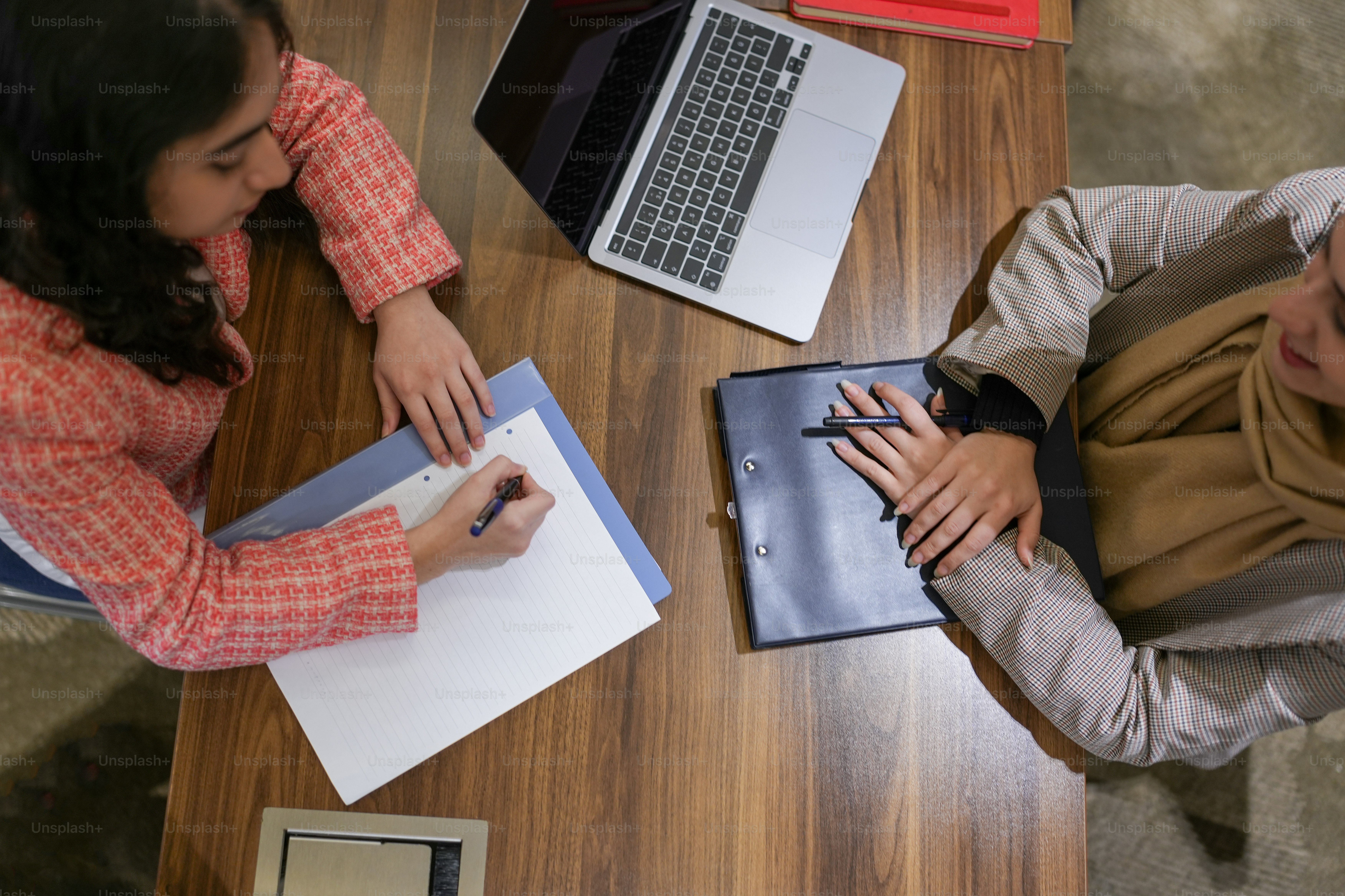 a couple of people sitting at a table with laptops