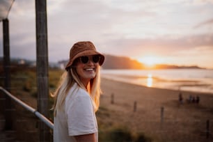 a woman wearing a hat and sunglasses on a beach