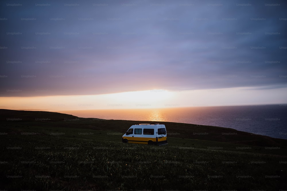 a van is parked on a grassy hill near the ocean