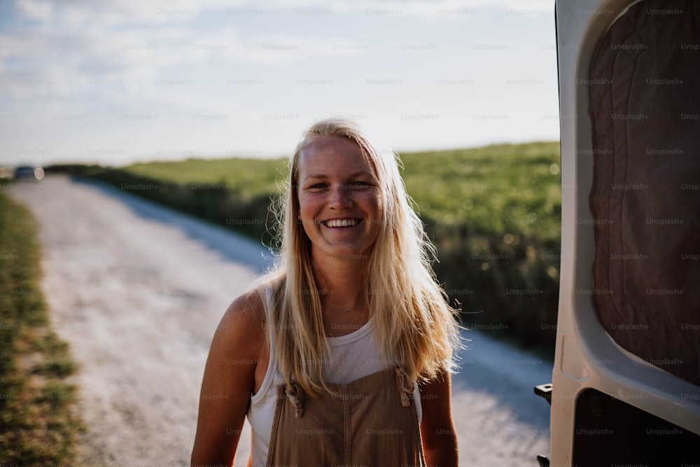 a woman standing next to a van on a dirt road