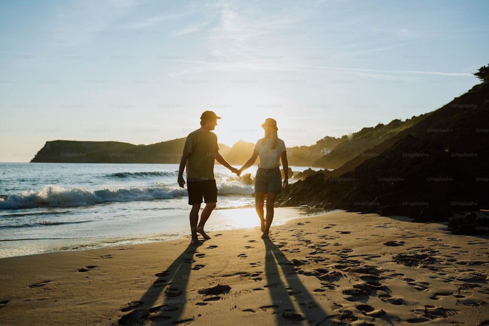 um homem e uma mulher que caminham em uma praia de mãos dadas