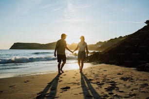 a man and a woman walking on a beach holding hands