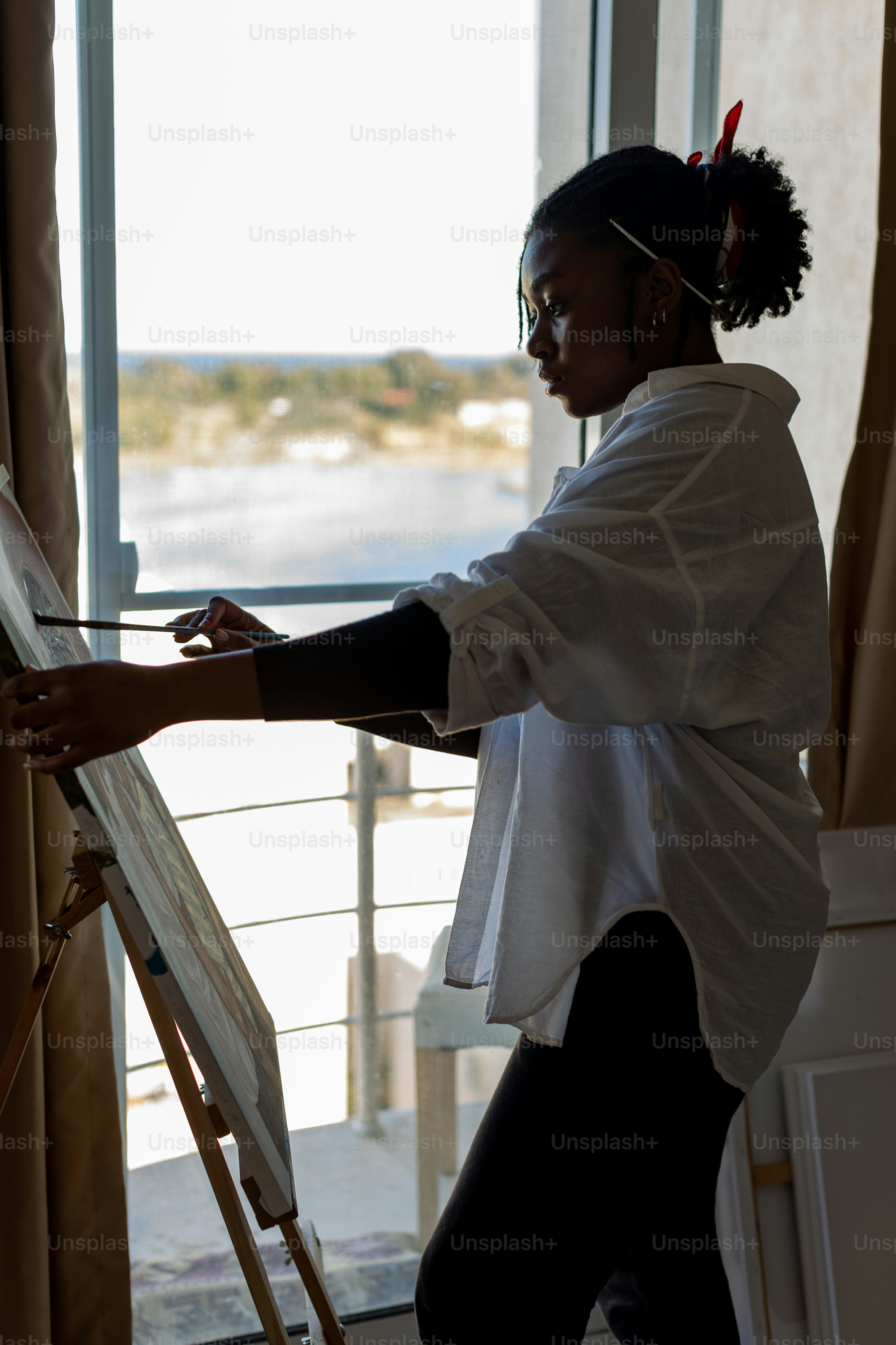a woman standing in front of a window painting