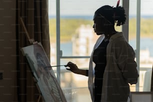 a woman standing in front of a window holding a paintbrush