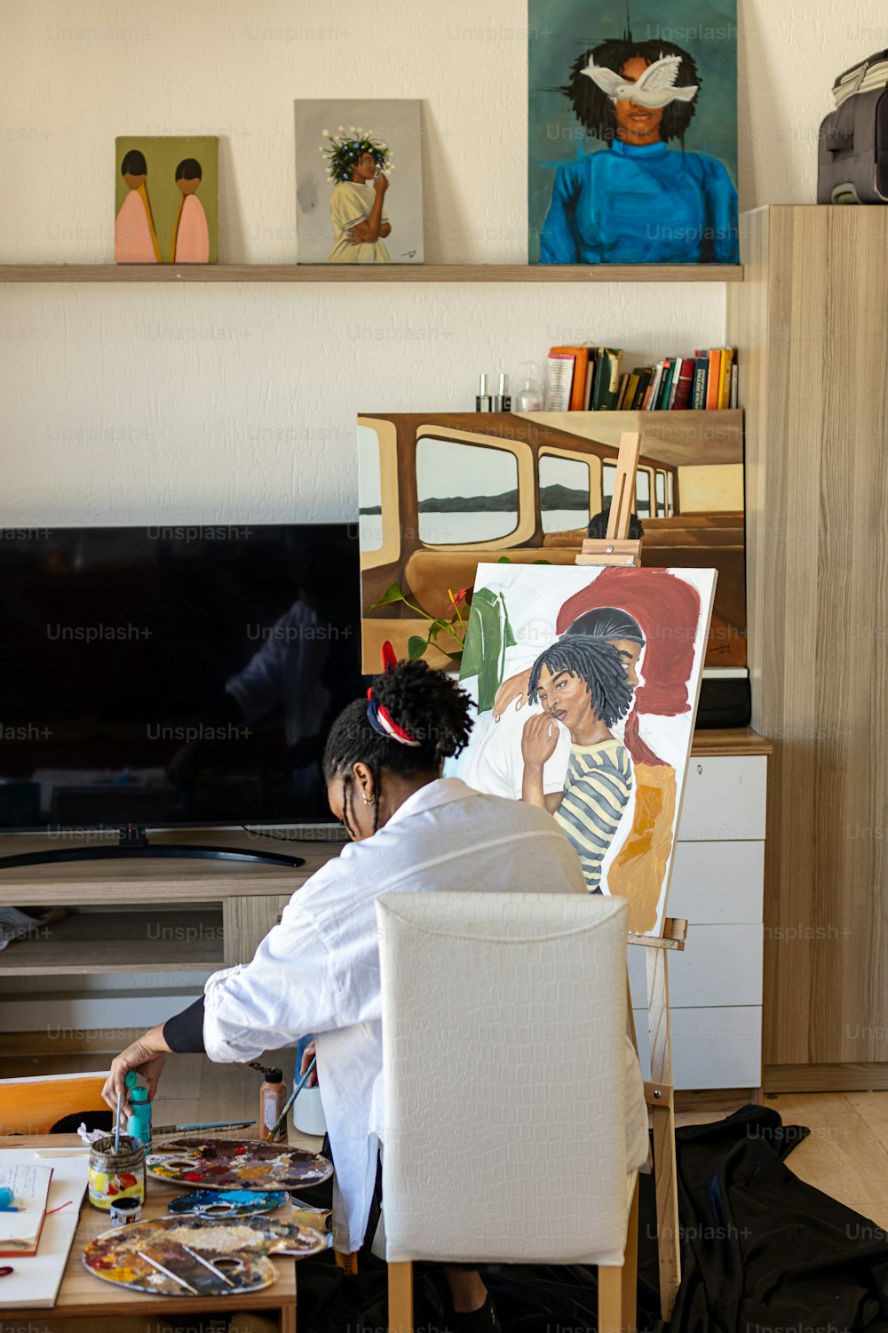 Eine Frau sitzt auf einem Stuhl vor einem Gemälde
