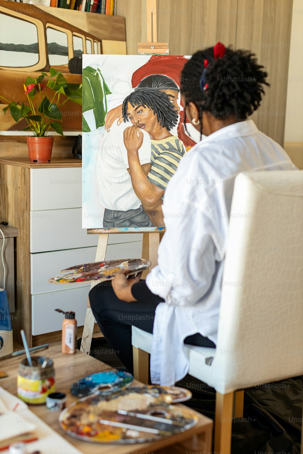 uma mulher sentada em uma cadeira na frente de uma pintura