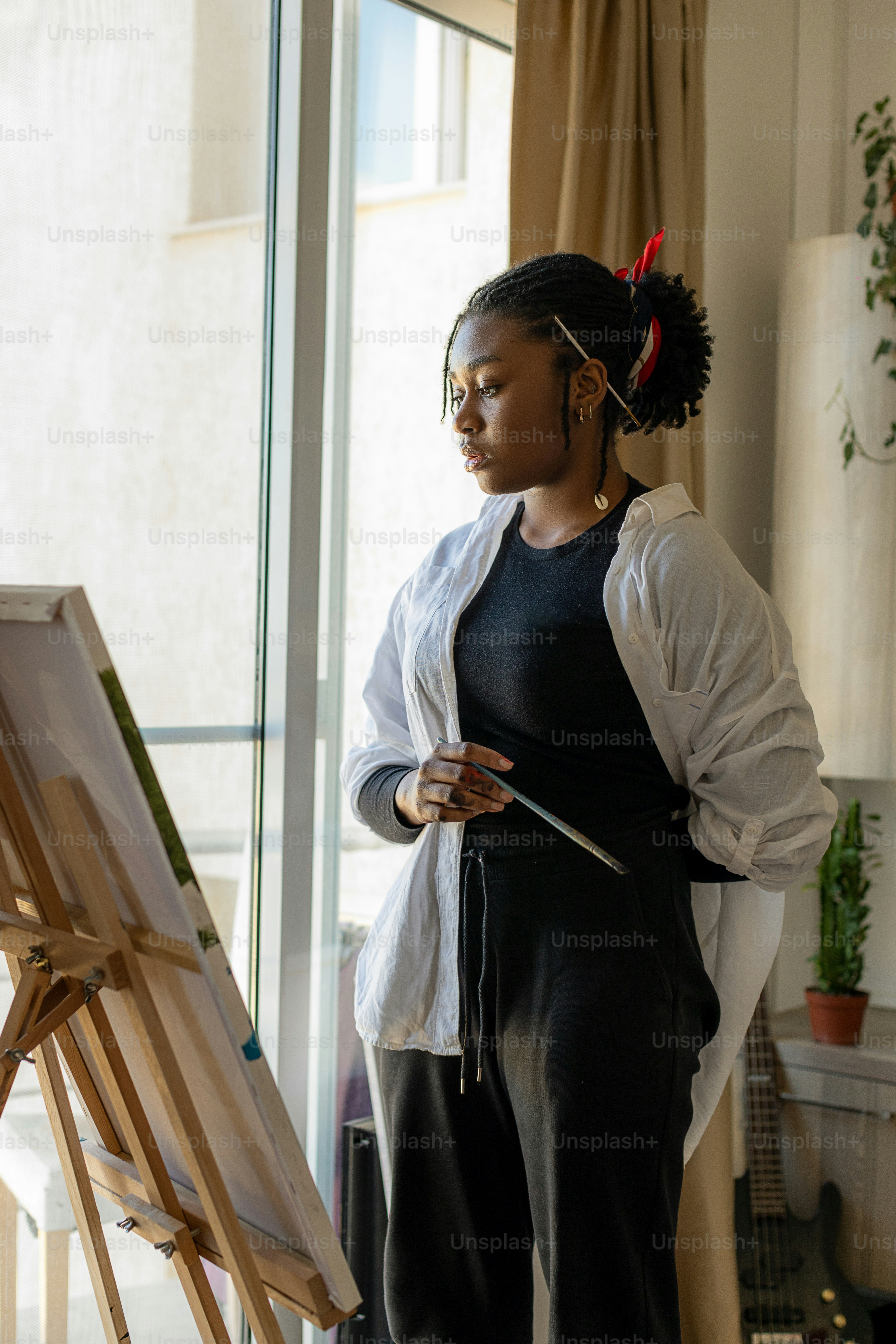 A woman standing in front of a painting on a easel photo – Artwork ...