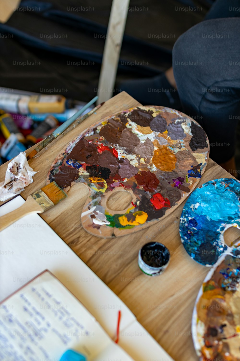 une table en bois surmontée de beaucoup de peinture et de papier