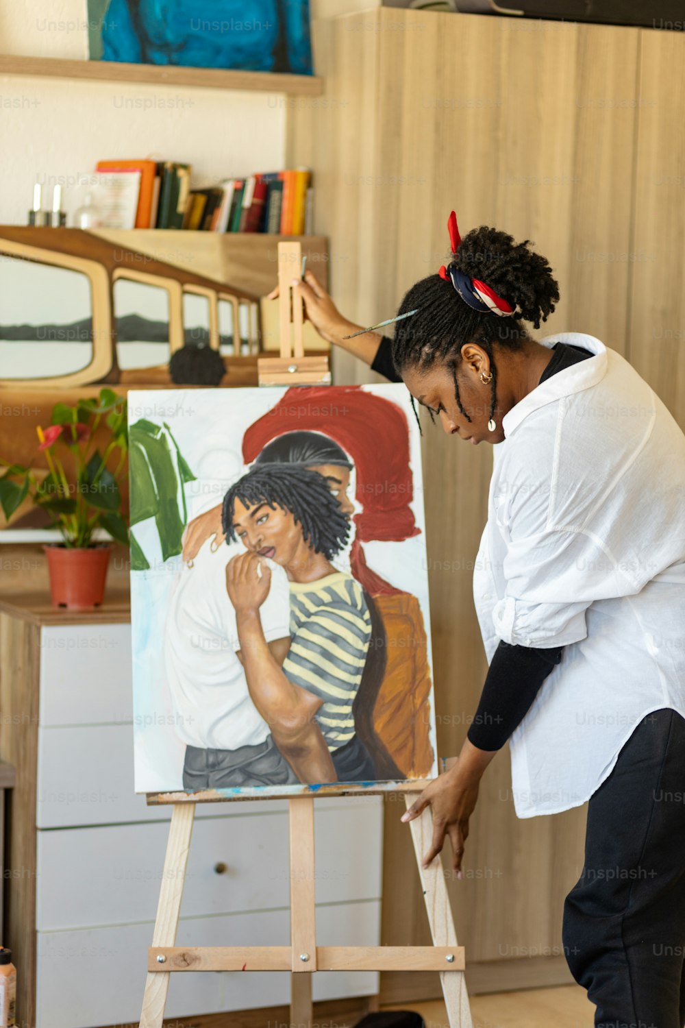 Una mujer parada frente a una pintura en un caballete
