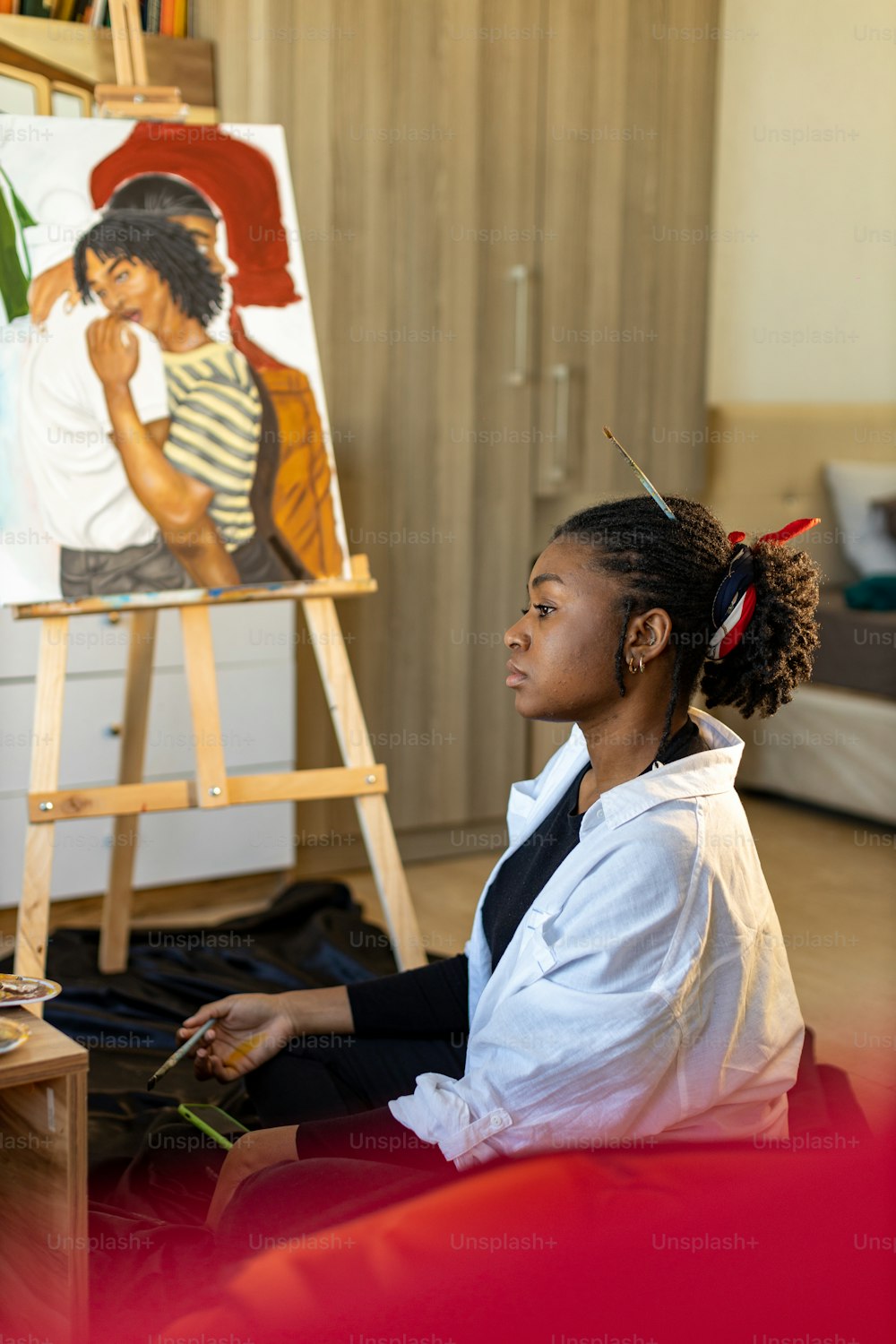 a girl sitting on the floor in front of a painting