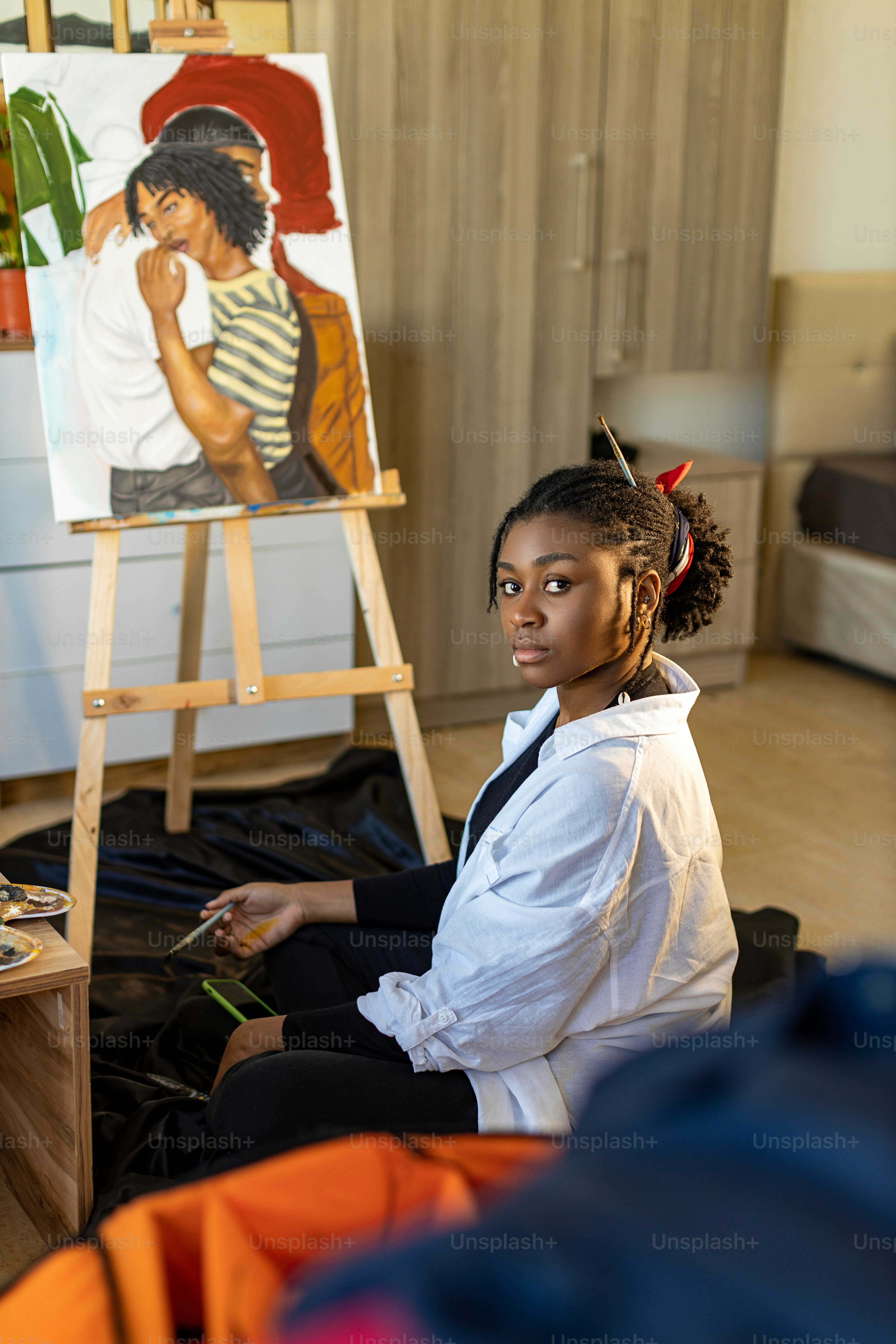a woman sitting on the floor in front of a painting