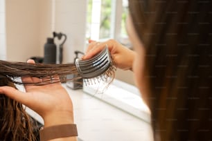 a woman is blow drying her hair with a comb