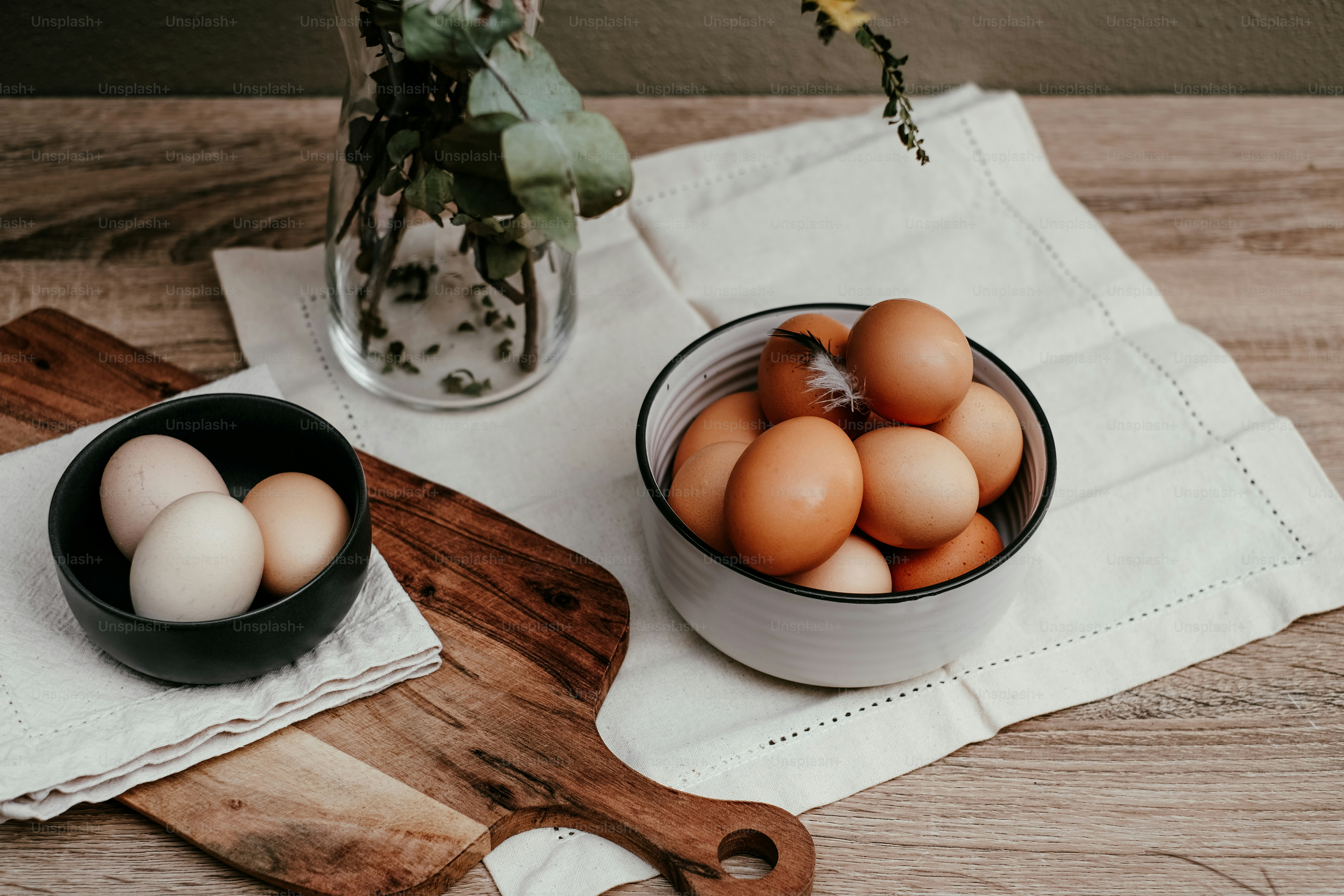 a bowl of eggs sitting on top of a wooden cutting board