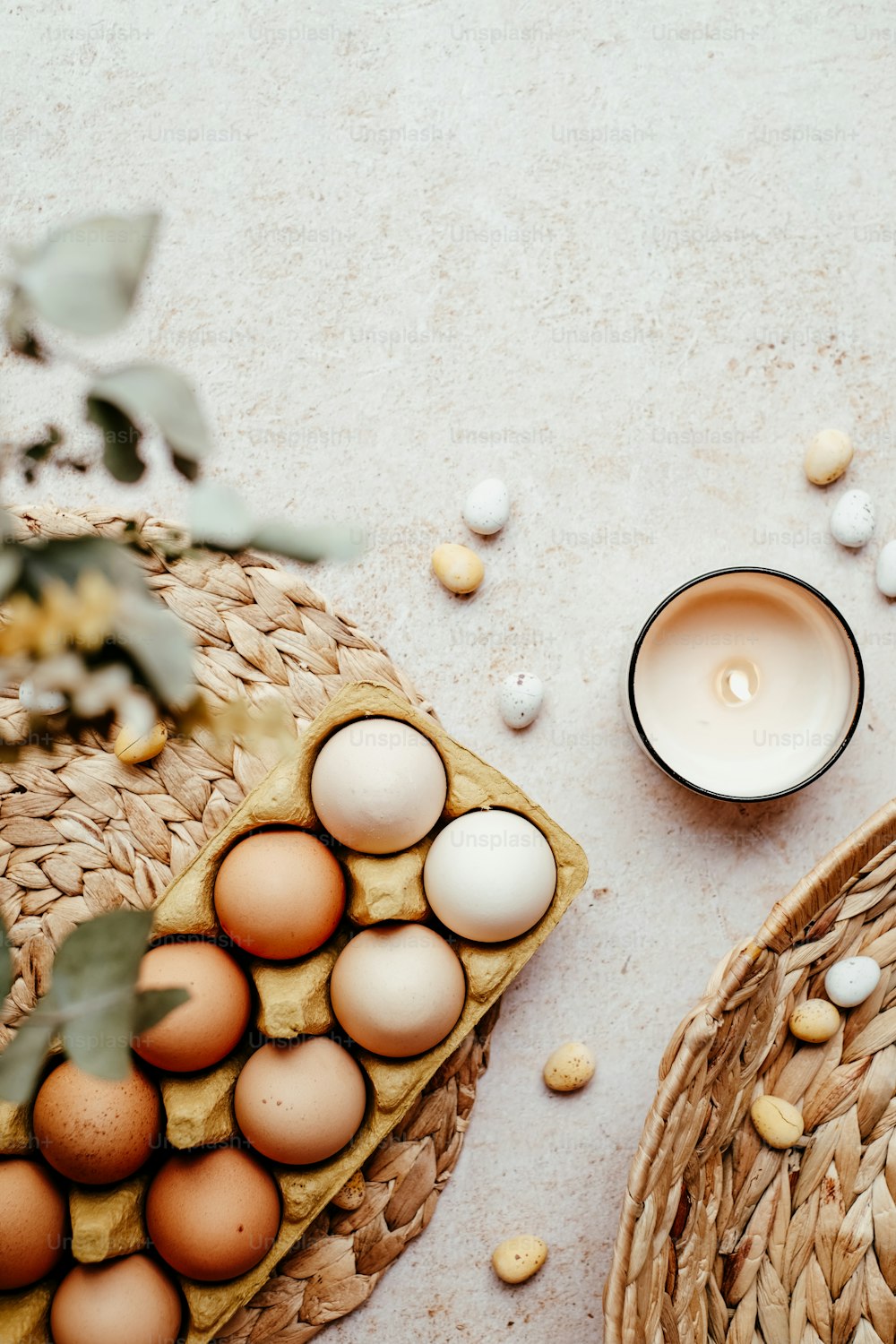uma cesta de ovos ao lado de uma vela em uma mesa