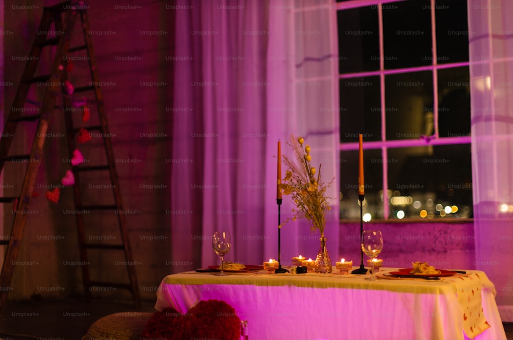 uma mesa com velas e flores na frente de uma janela