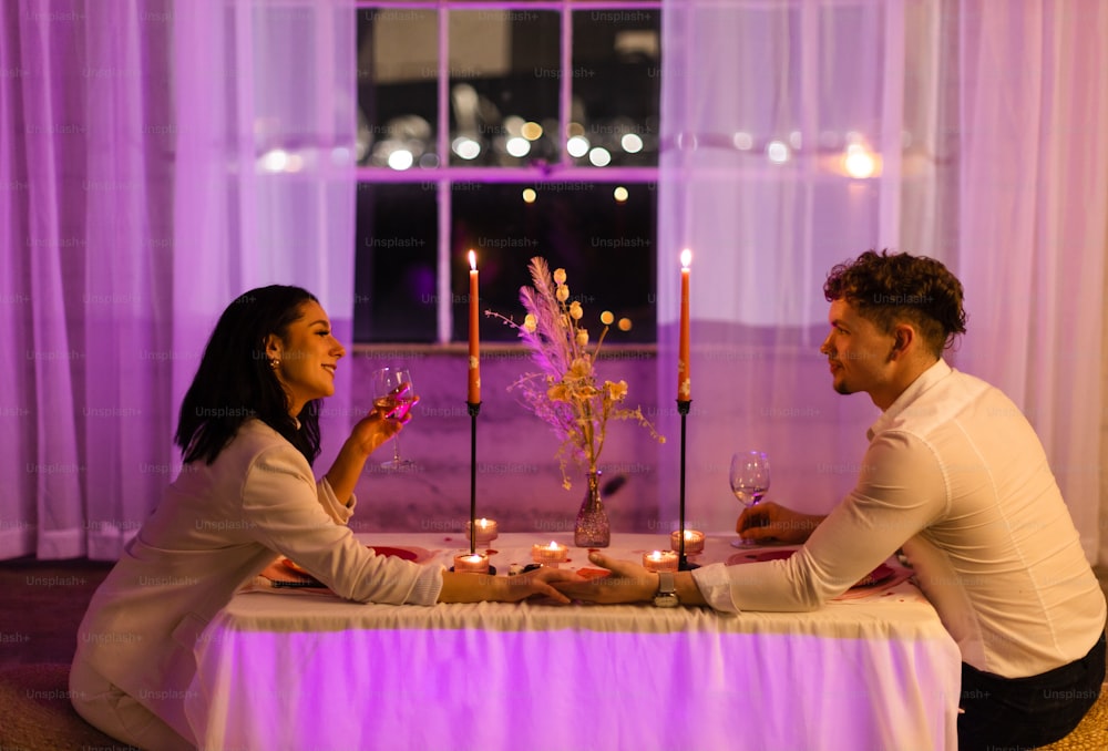 Un hombre y una mujer sentados en una mesa con velas