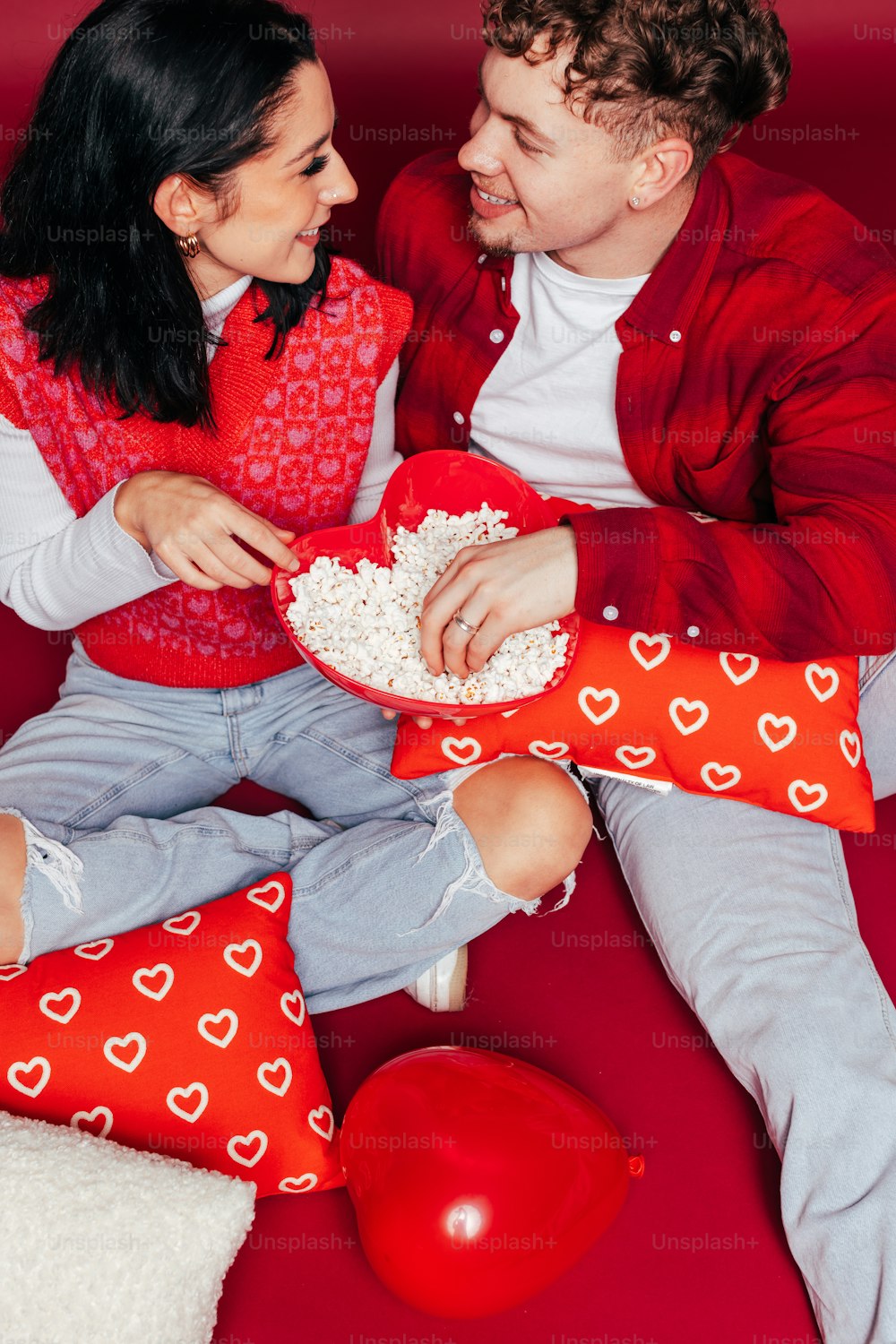 um homem e uma mulher sentados em um sofá vermelho