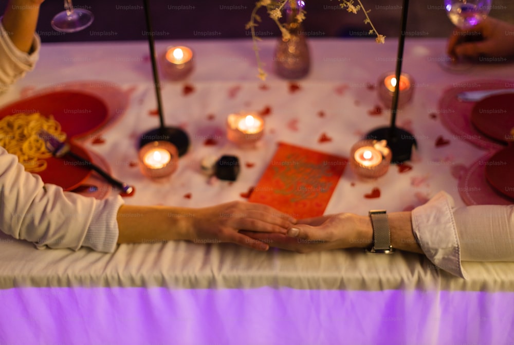 a couple holding hands over a table with candles