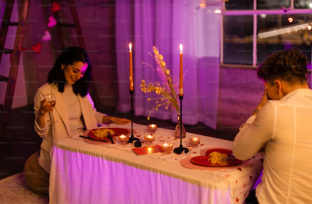 a man and a woman sitting at a table with candles