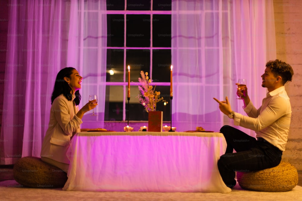 um homem e uma mulher sentados em uma mesa com taças de vinho