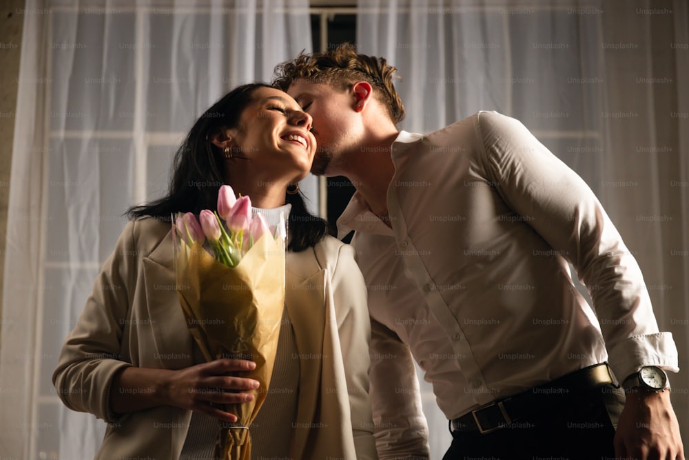 um homem beijando uma mulher enquanto segurava um buquê de flores