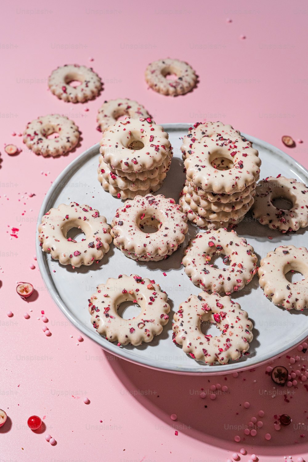 a plate of sprinkled donuts on a pink surface