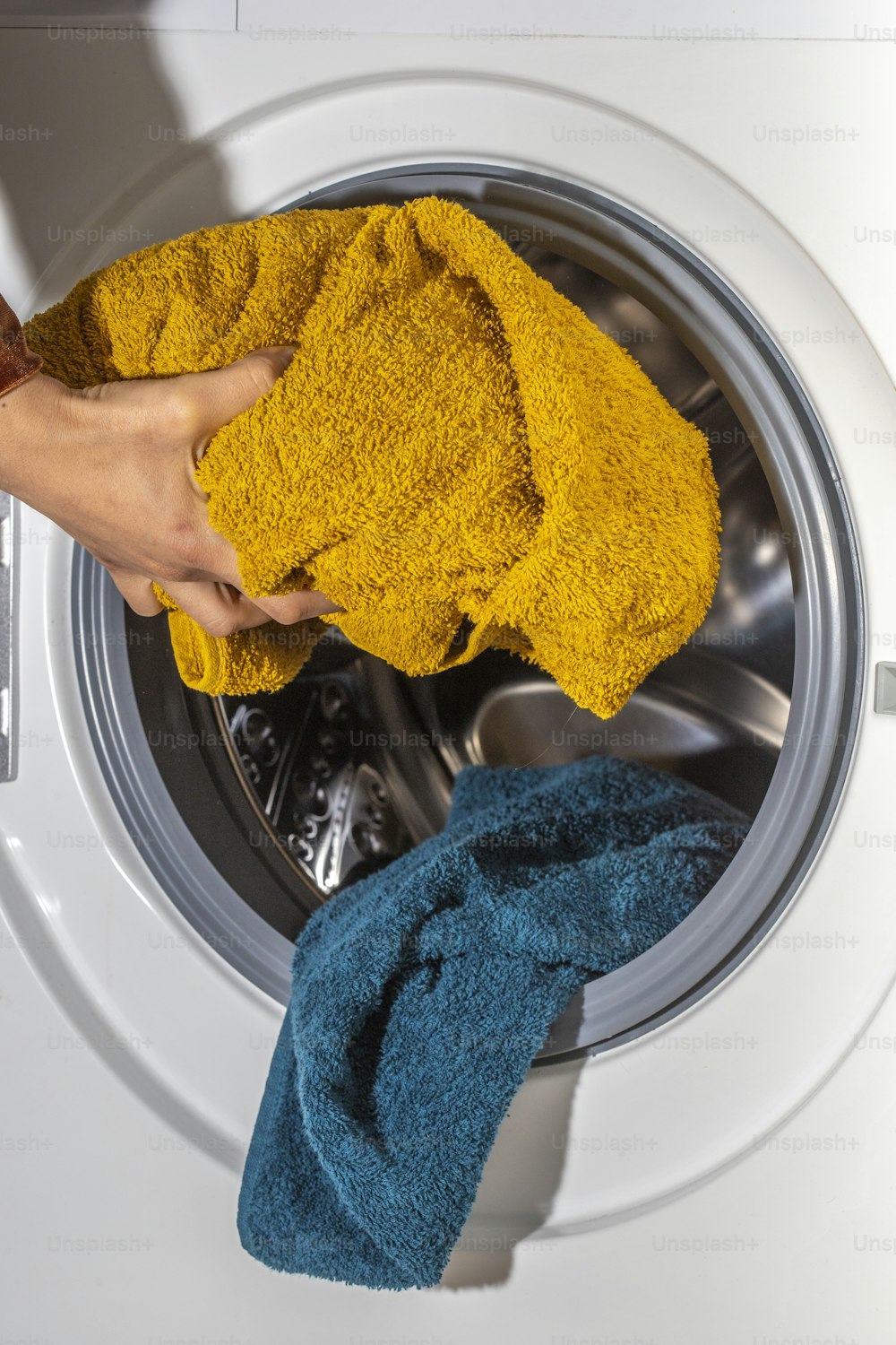 eine Person, die ein gelbes Handtuch neben einer Waschmaschine hält