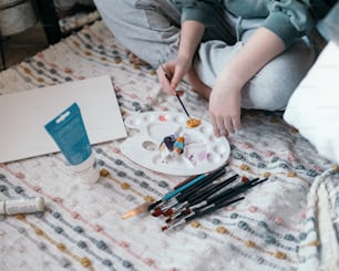 a person sitting on a bed holding a paintbrush