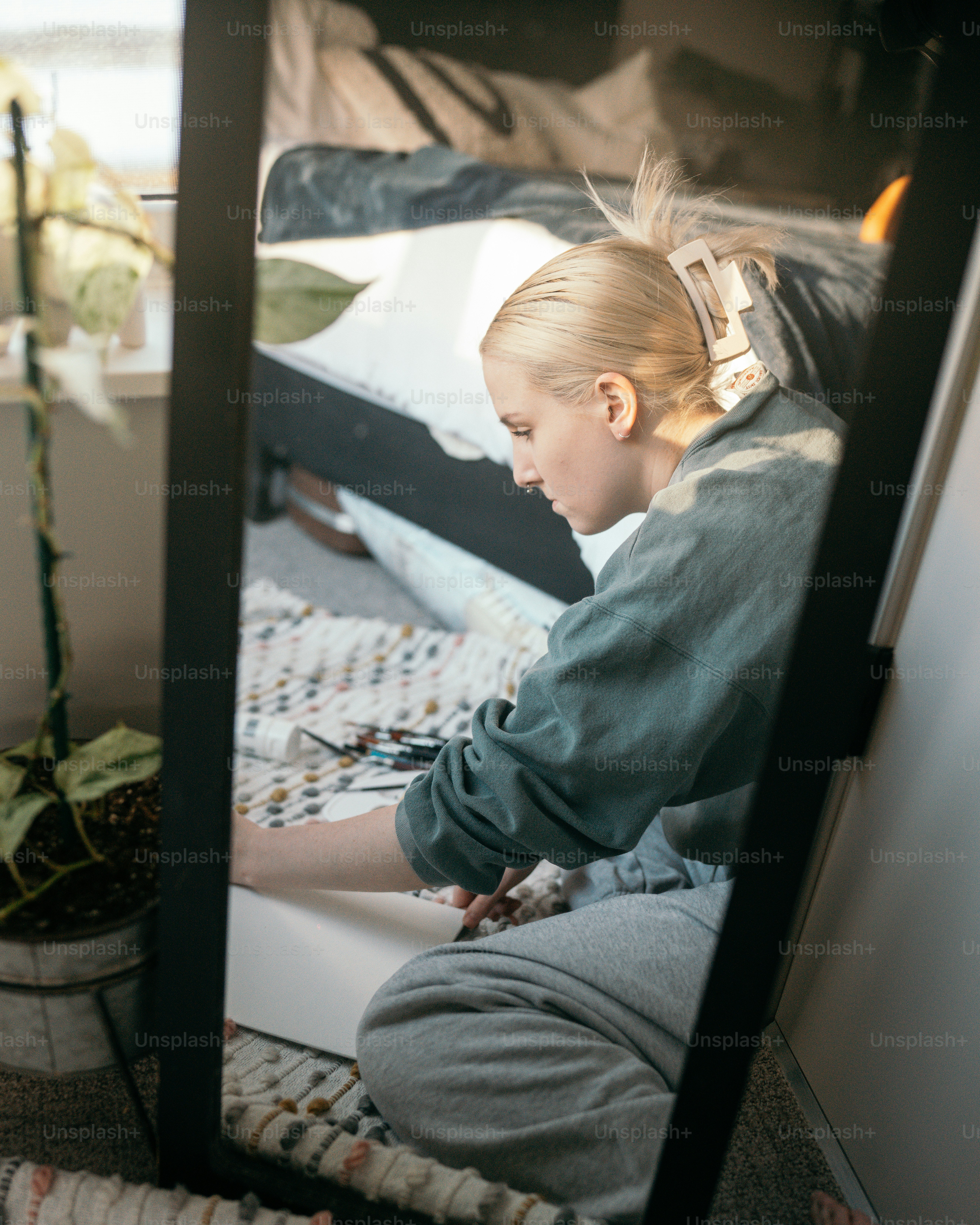 a young girl sitting on a bed looking at her cell phone