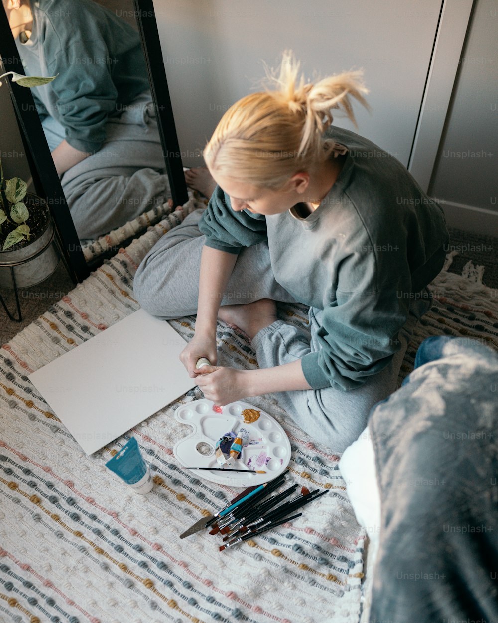 a woman sitting on the floor painting a picture