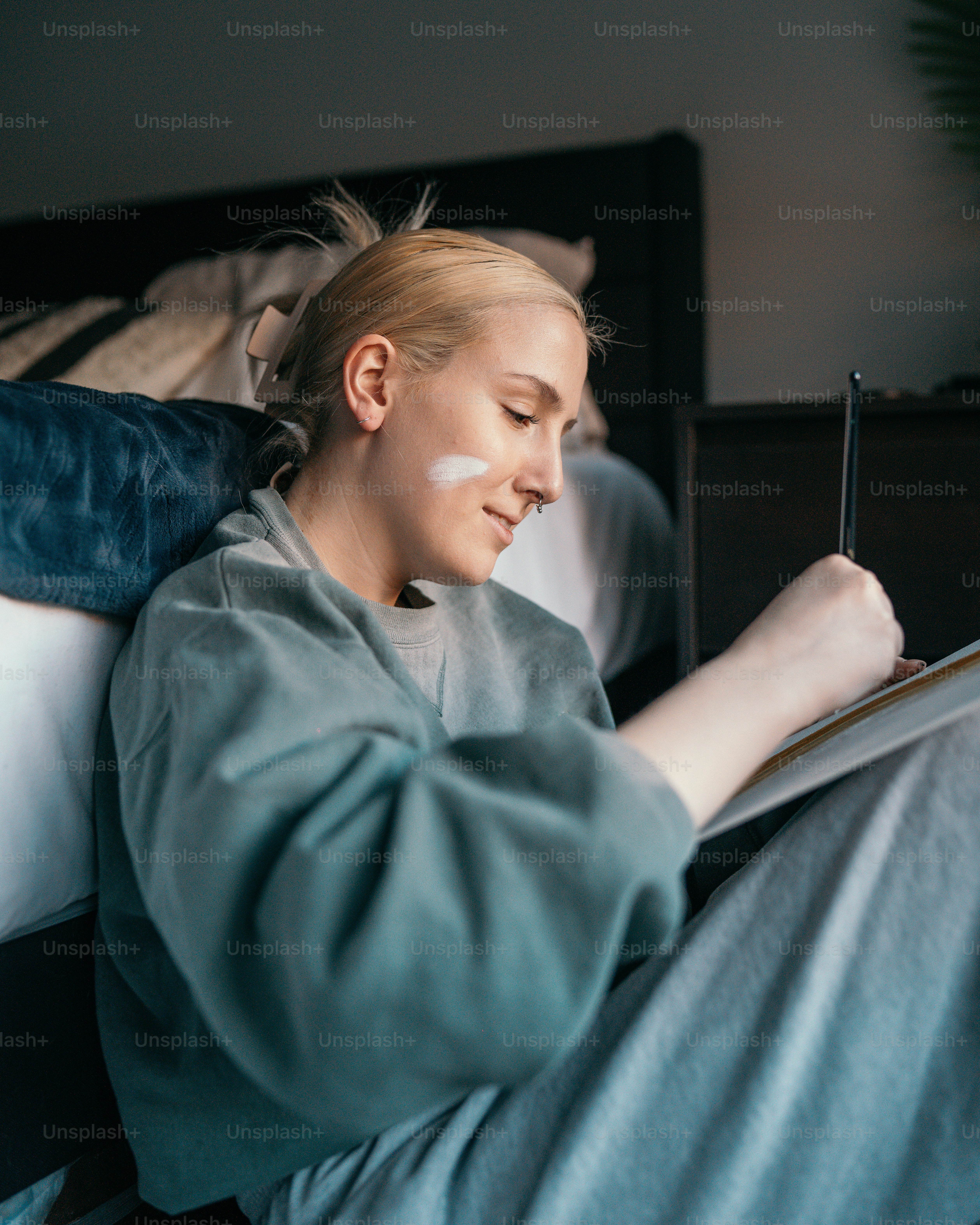 a woman sitting on a bed writing on a piece of paper