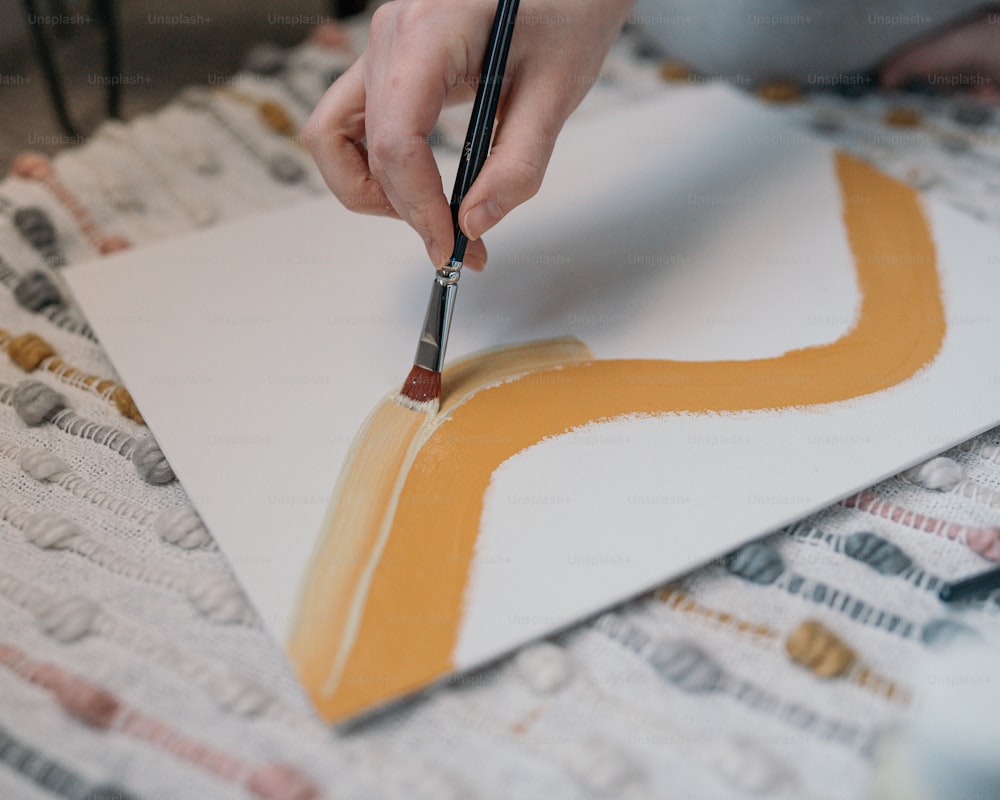 a person using a brush to paint a piece of paper