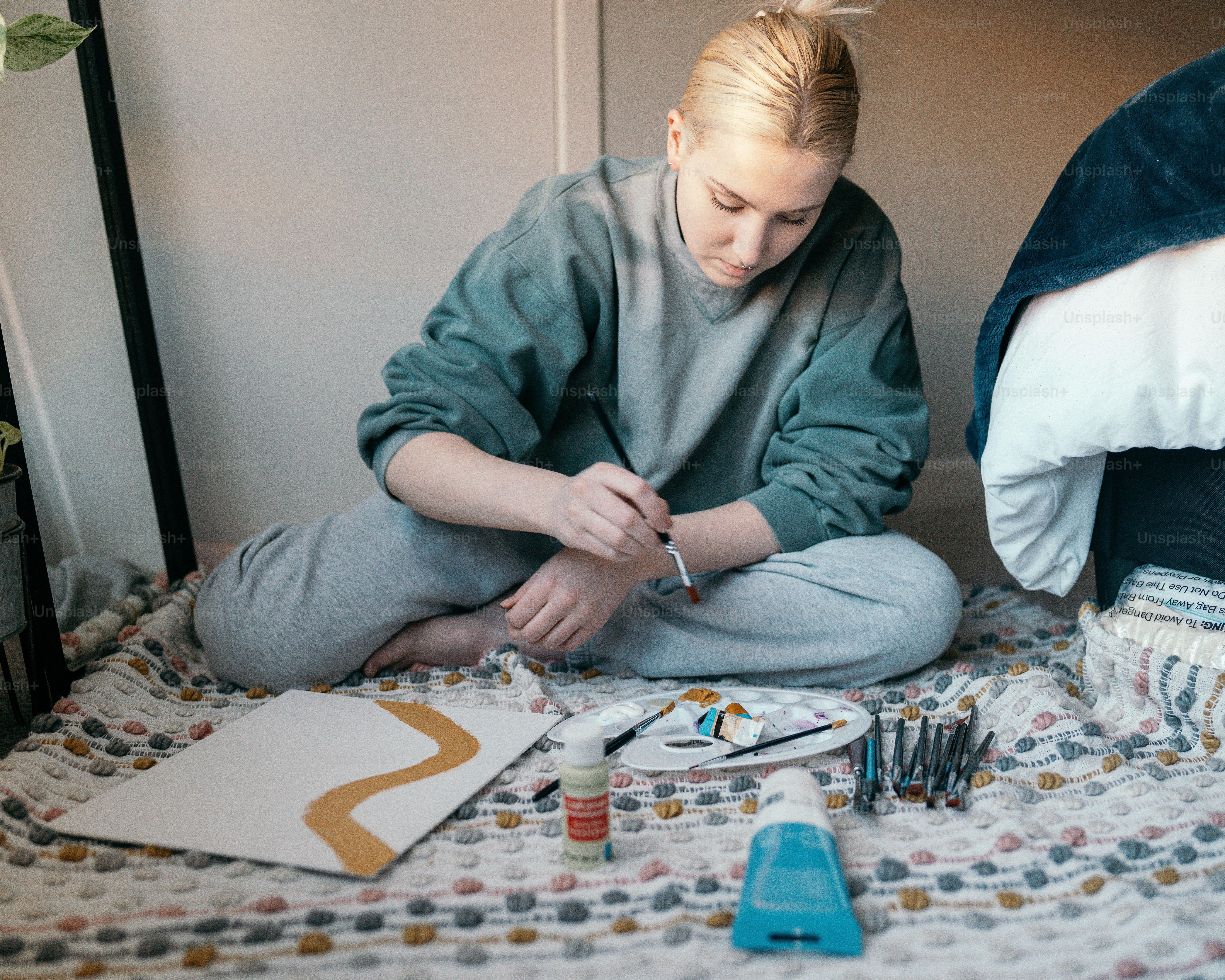 a woman sitting on a bed working on a project