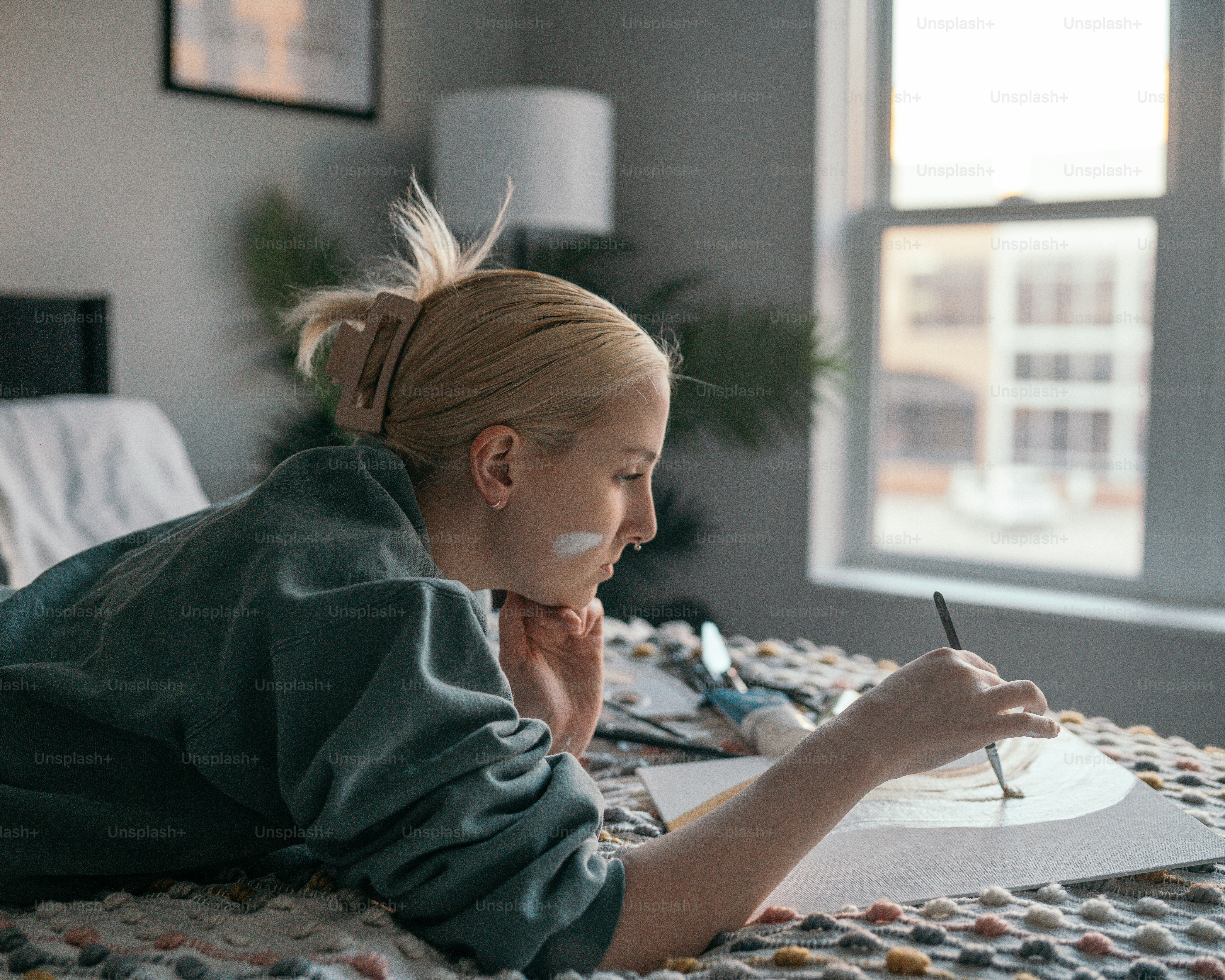a woman laying on a bed writing on a piece of paper