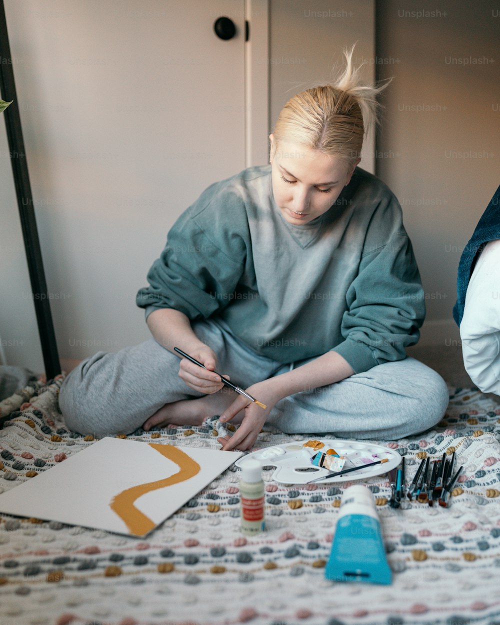 a woman sitting on a bed painting a picture