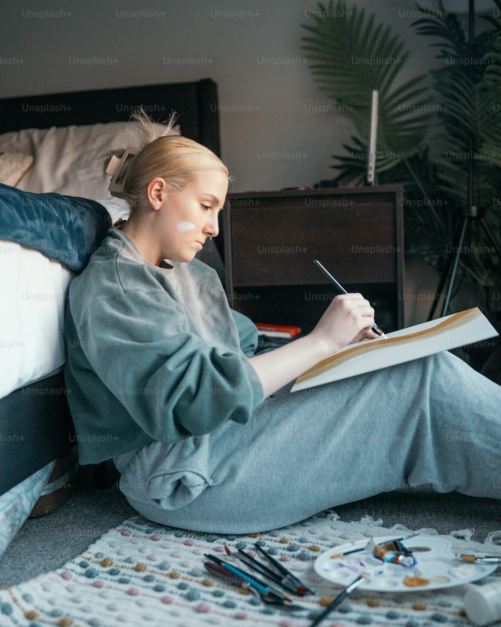 a woman sitting on a bed writing in a notebook