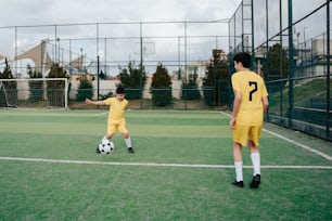 a couple of young men kicking around a soccer ball