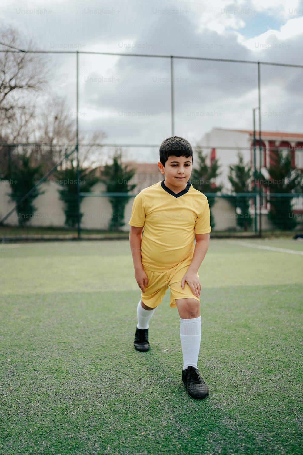 um menino em um uniforme de futebol em pé em um campo