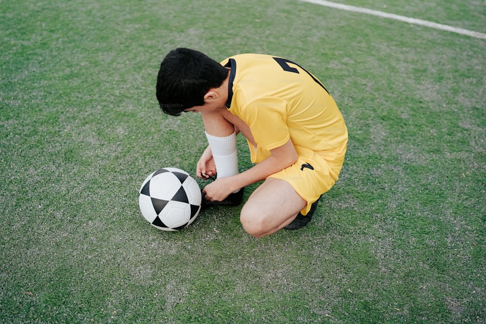 a young man kneeling down next to a soccer ball