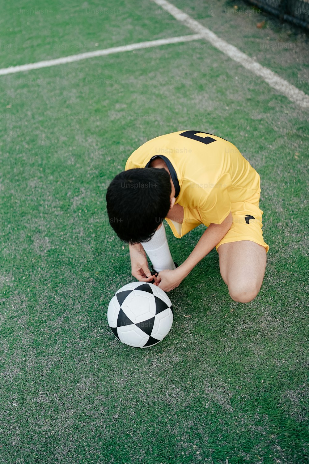 Un hombre arrodillado junto a un balón de fútbol