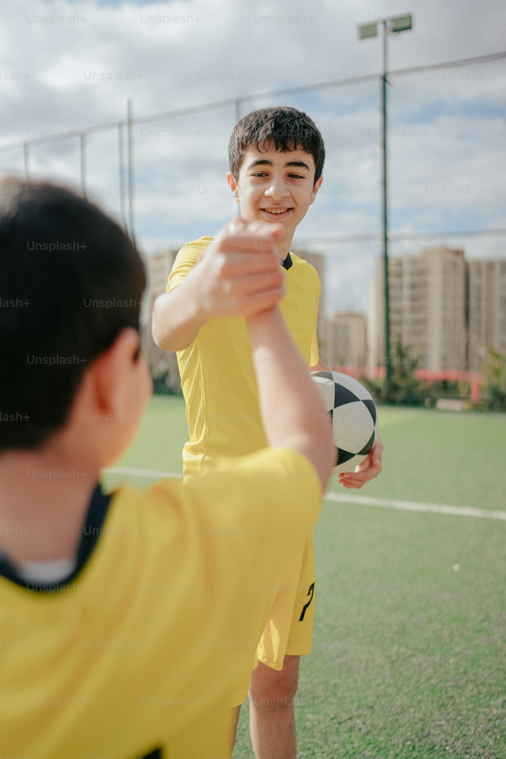 a boy in a yellow shirt holding a soccer ball