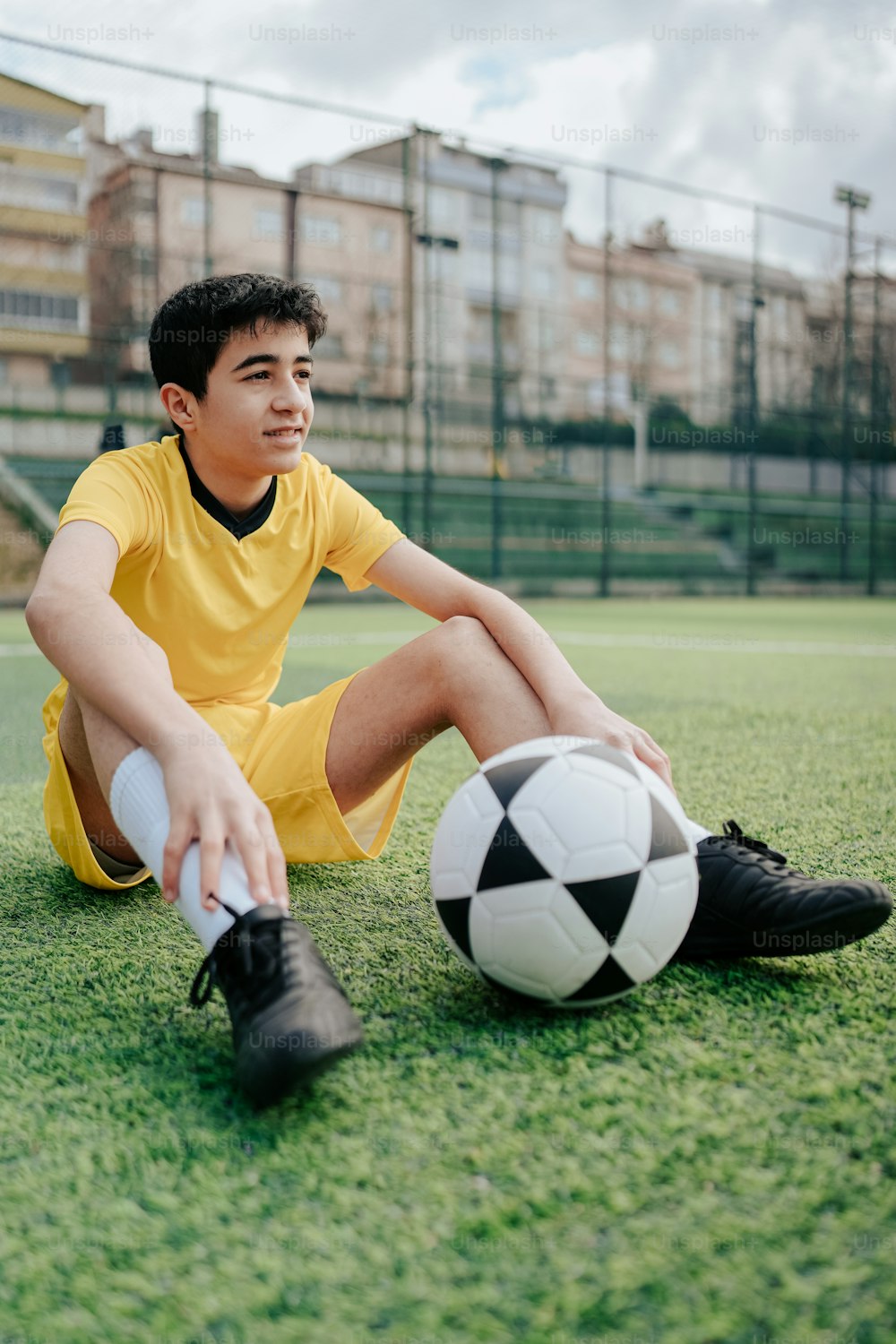 a young man sitting on the ground with a soccer ball