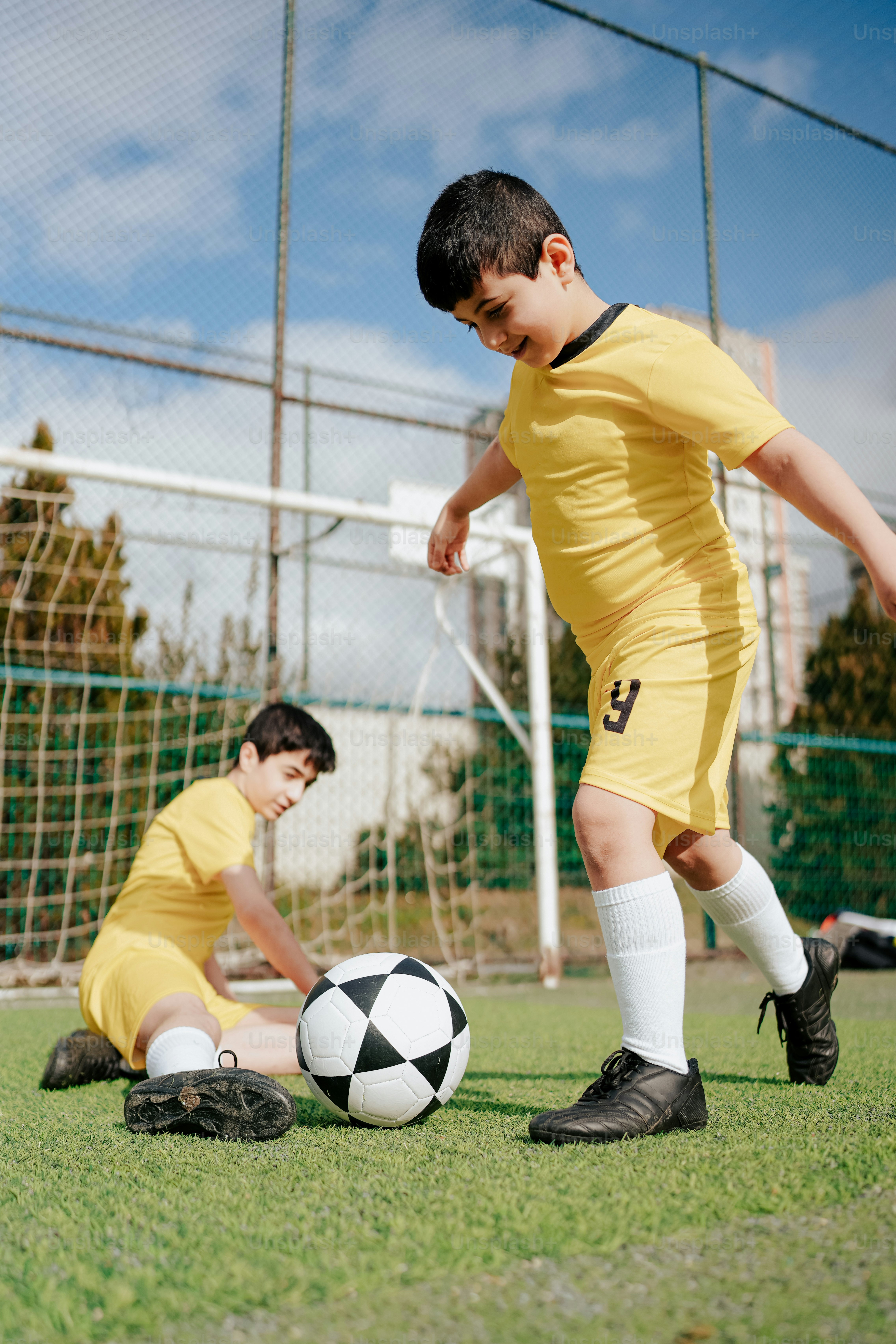 a couple of young men kicking around a soccer ball