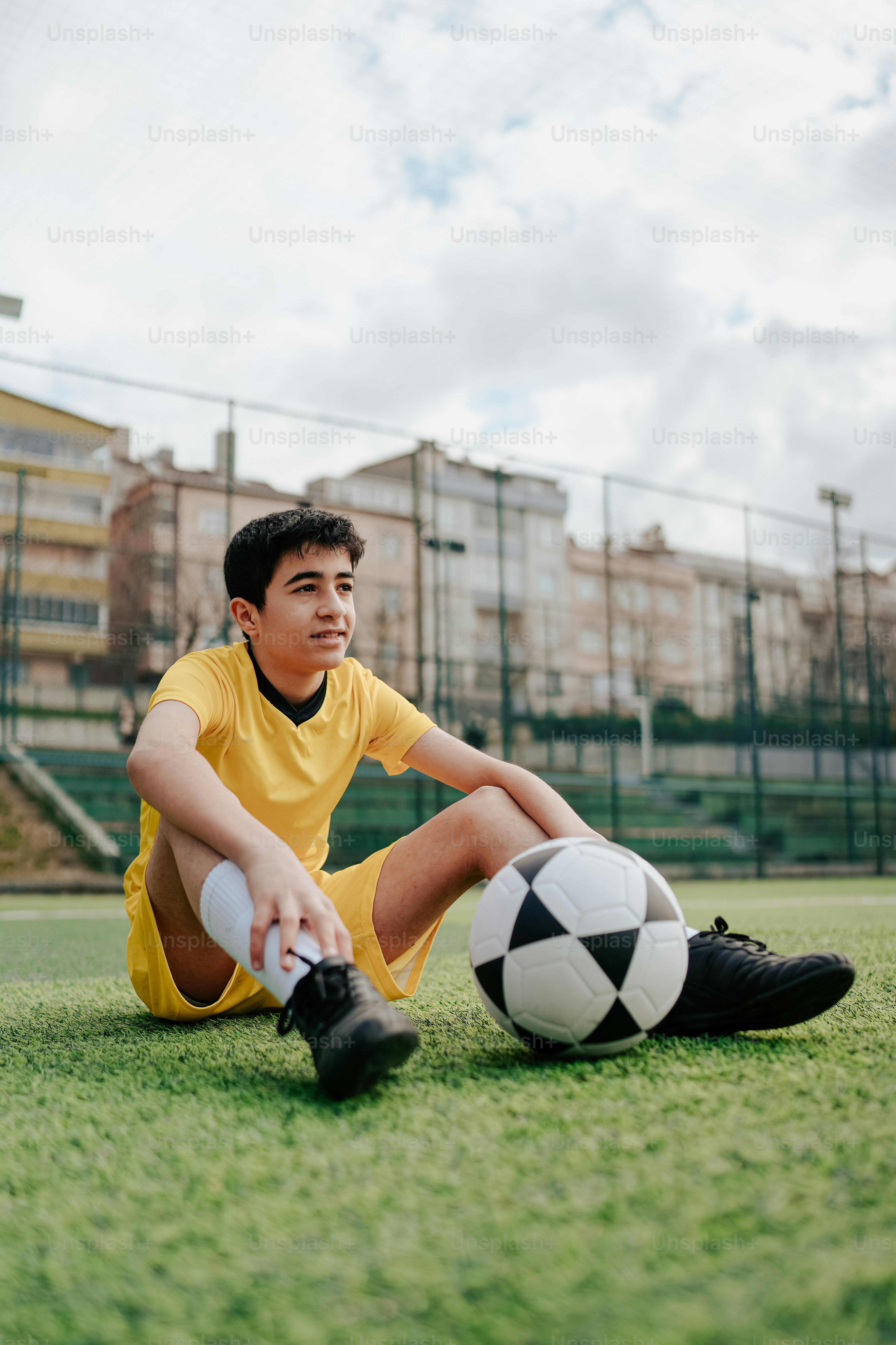 a young man sitting on the ground with a soccer ball