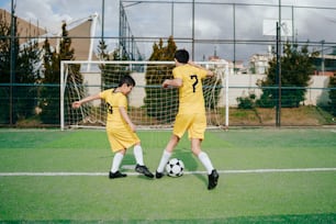 a couple of young men kicking a soccer ball around a field