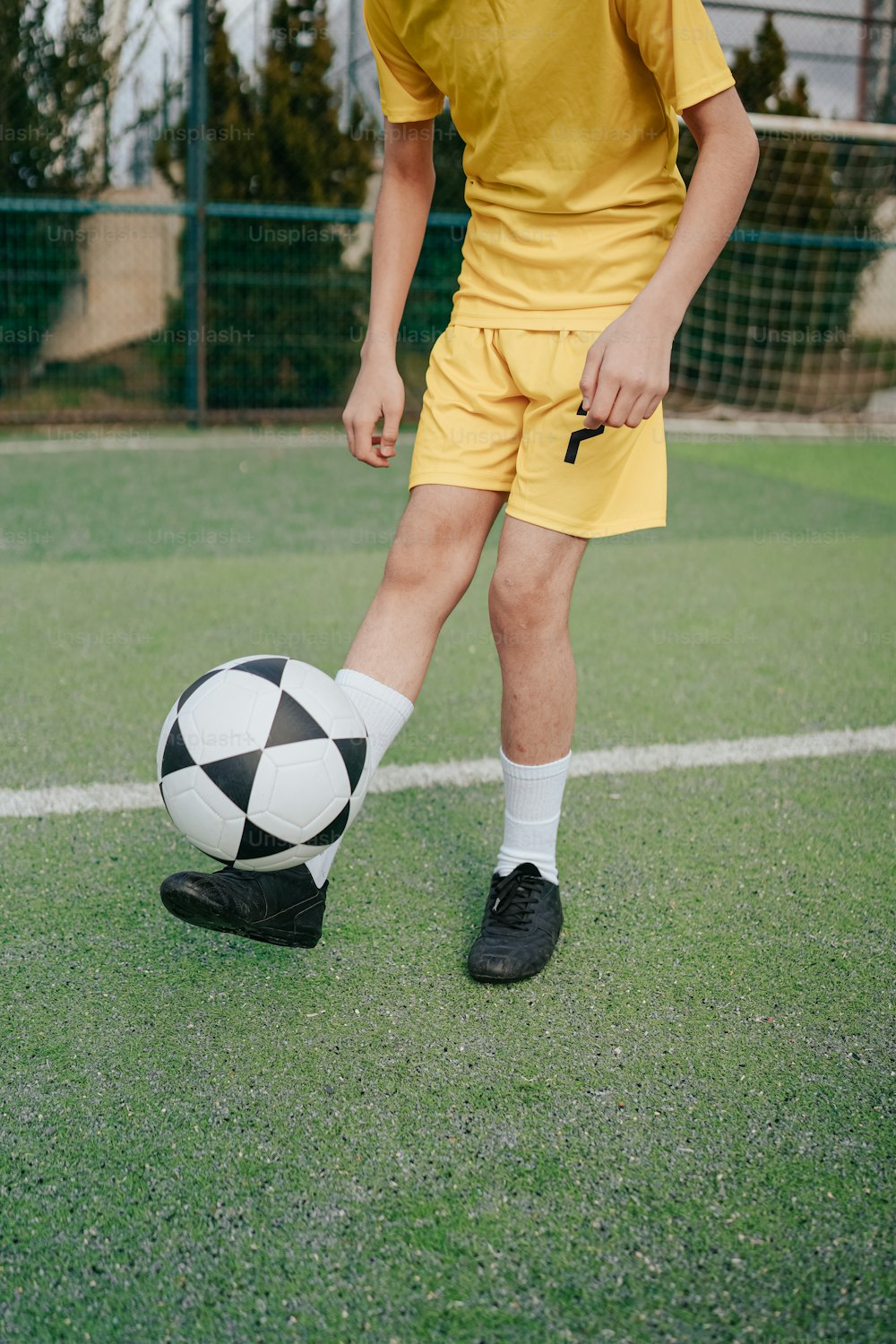 a young man in a yellow uniform kicking a soccer ball