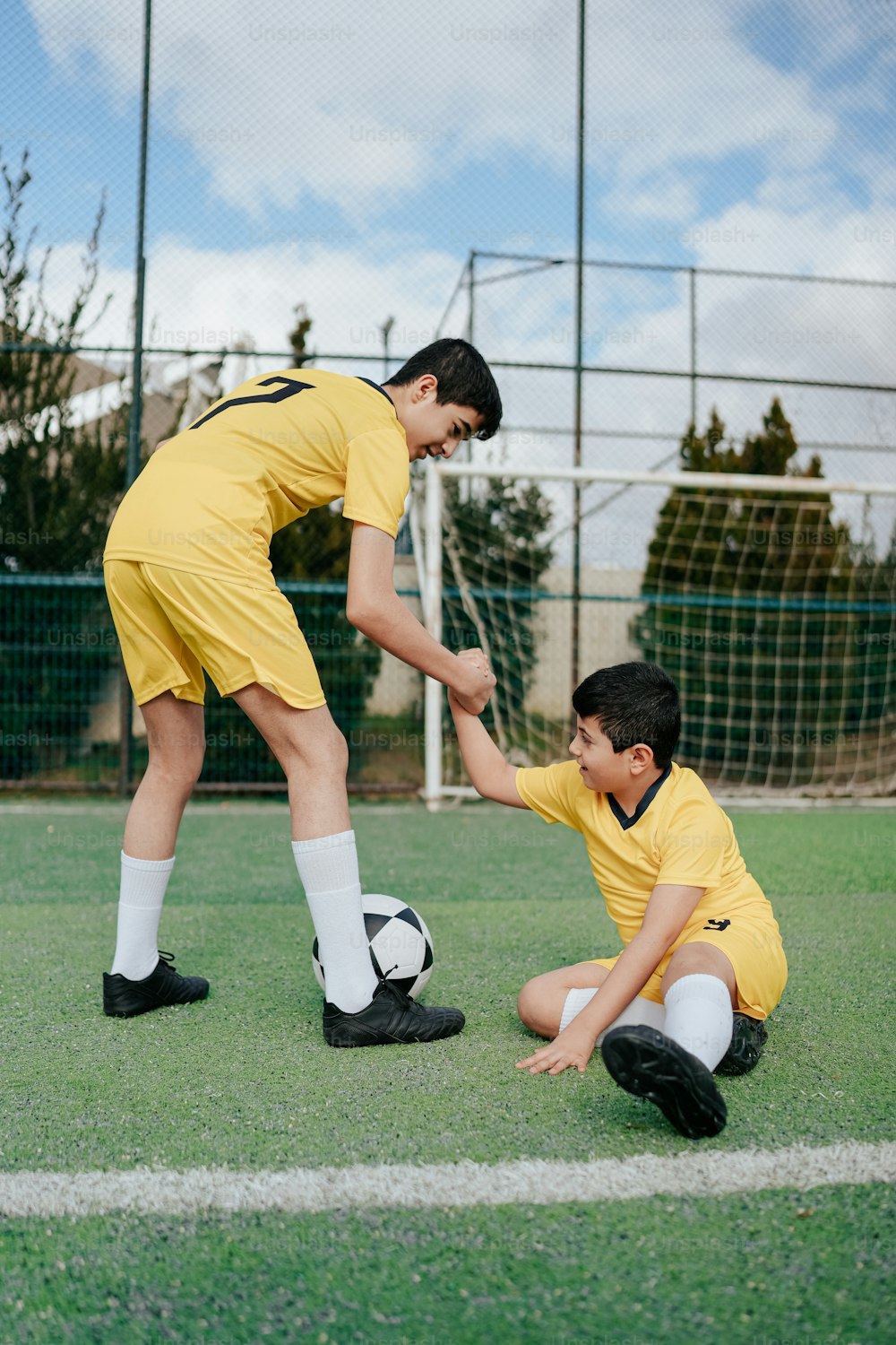 Ein Mann, der einem kleinen Jungen mit einem Fußball hilft