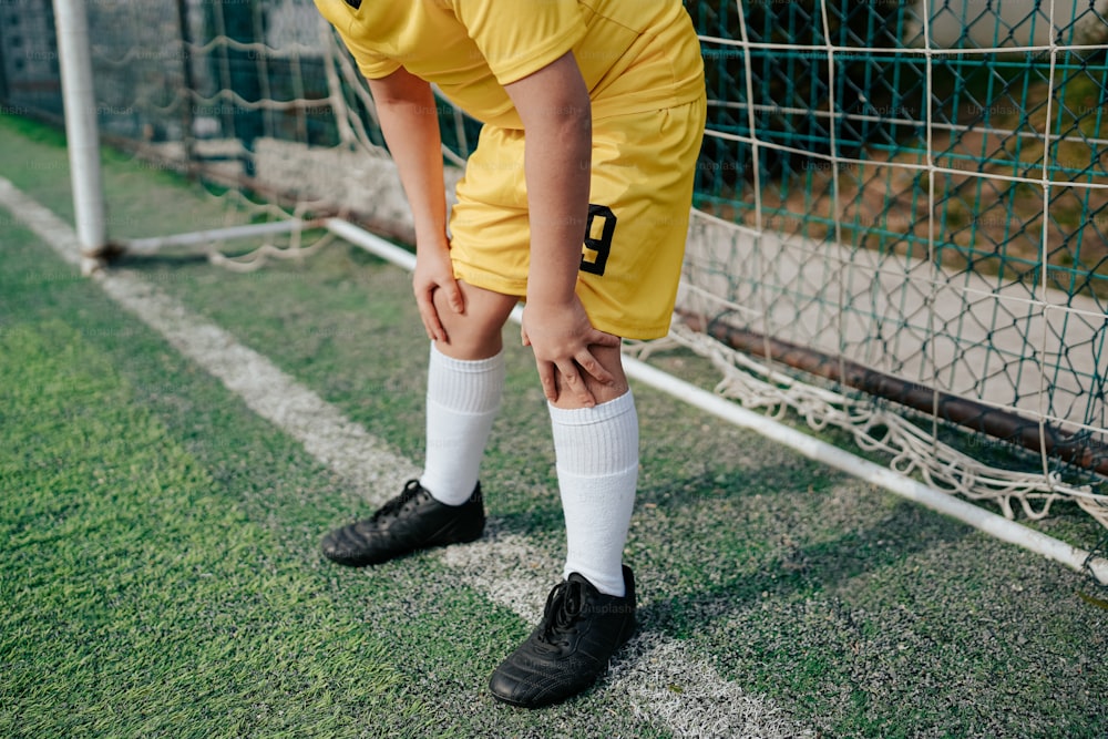 a young boy in a soccer uniform kneels in front of a soccer goal