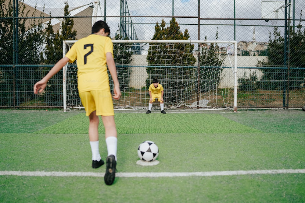 Un giovane ragazzo che calcia un pallone da calcio su un campo di calcio