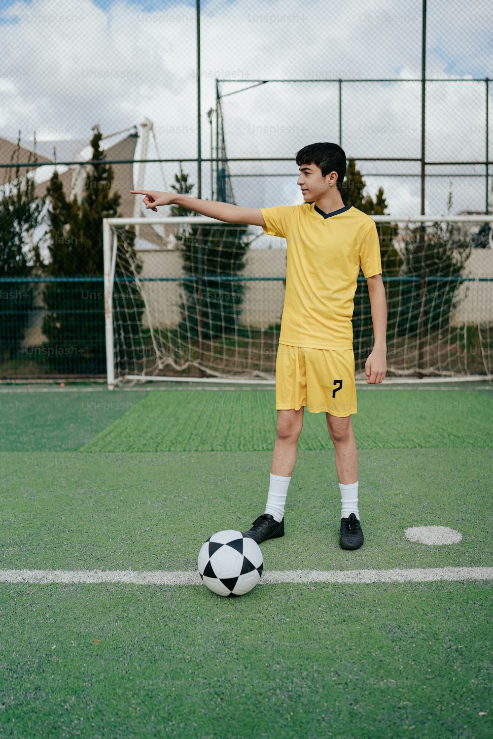 a young man in a yellow uniform kicking a soccer ball